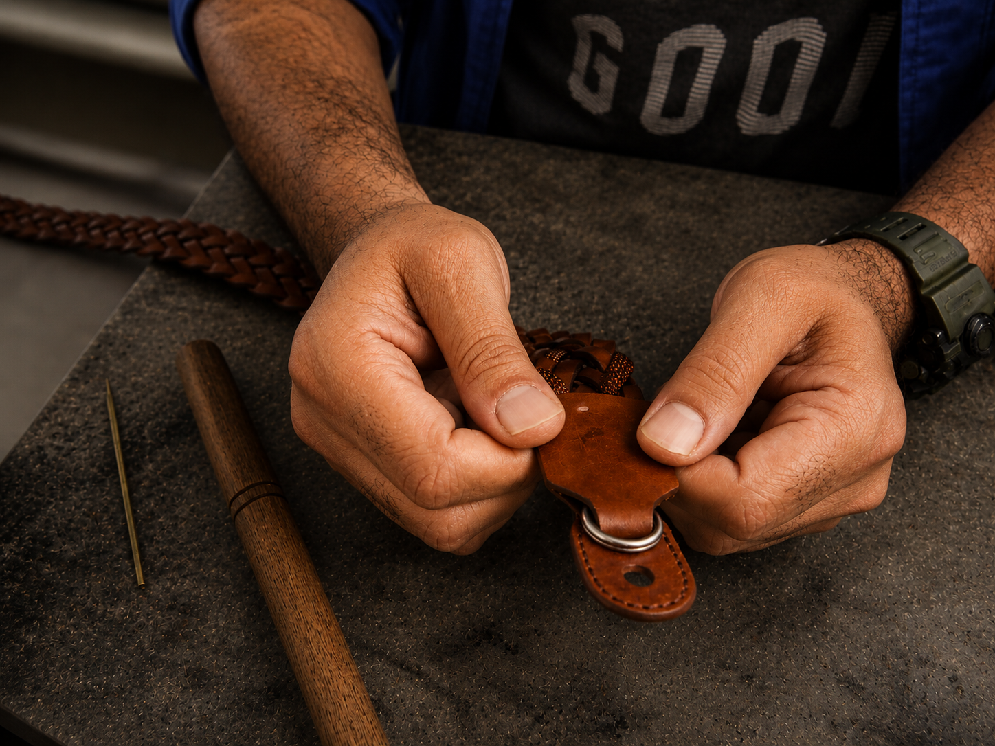 Mains d'artisan contrôlant une pièce cuir et anneau métal à l'établi